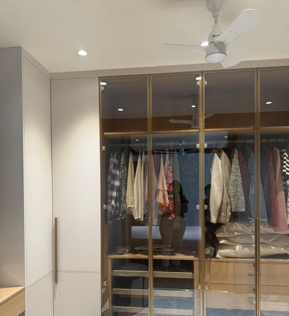 Walk-in wardrobe with brass-trimmed glass-front cabinetry and built-in drawers